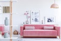 Real photo of a pink couch with pillows in front of a shelf with