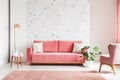 Real photo of a pink, velvet sofa, plant, coffee table with pot