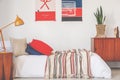 Real photo of a red and blue bedroom interior with a bed, lamp and posters Royalty Free Stock Photo