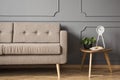 Real photo of a retro sofa standing next to a small table with a