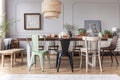 Real photo of a rustical dining room interior with a wicker lamp, table, chairs and plants