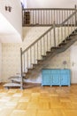 Real photo of a simple corridor with gray, wooden stairs, blue c