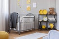 Real photo of a toddler room interior with a crib, honeycombs and teddy bear