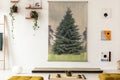 Real photo of a tree graphic hanging on white wall above a tatami mat in simple japanese interior with green tea set and yellow c