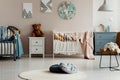 Real photo of two pillows on a round, white rug in pastel baby room interior with two beds, teddy bears and paintings Royalty Free Stock Photo