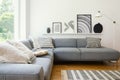 Real photo of white Scandi sitting room interior with metal lamp, corner sofa with cushions and modern art posters Royalty Free Stock Photo