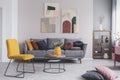 Real photo of a yellow chair and gray couch with pillows in a modern living room interior Royalty Free Stock Photo