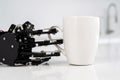 Real robot hand and white cup of coffee. Concept of robotic process automation