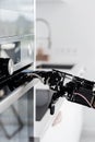Real robot's hand and electric oven. Concept of robotic process automation
