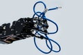 Real robot's hand holding blue Ethernet cable with rj45 connector on grey background Royalty Free Stock Photo