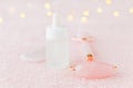 Real rose quartz facial roller, gua sha massage stone and face serum, selective focus