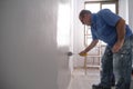 Real senior house painter painting a grey wall with a paint roller. Real dirty worker Royalty Free Stock Photo