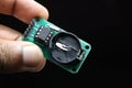 Real time clock module or RTC DS1302 module held in hand isolated on black background