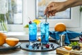 Real woman preparing a blue gin tonic cocktail with ice a mix of alcohol near the window on the table near window in the sun Royalty Free Stock Photo