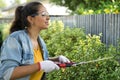 Real woman working on the yard cutting the yard with hedge shear while smiling