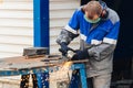 Real worker in working clothes grinds metal surface and sparks fly. person at work