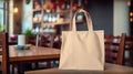 Realistic Beige Tote Canvas Fabric Bag Set-up In A Restaurant, Coffee Shop Interior, Tote Mock Up Blank. Beige Tote Bag Template