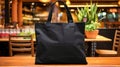 Realistic Black Tote Canvas Fabric Bag Set-up In A Restaurant, Coffee Shop Interior, Tote Mock Up Blank. Black Tote Bag Template