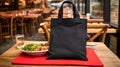 Realistic Black Tote Canvas Fabric Bag Set-up In A Restaurant, Coffee Shop Interior, Tote Mock Up Blank. Black Tote Bag Template
