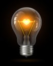 Realistic glowing light bulb with transparency isolated on black. Inside the lamp is incandescent filament with glowing heart.