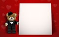 Realistic little cute smiling bear doll wear tuxedo character holding a gift box and standing next to white frame on red backgroun Royalty Free Stock Photo