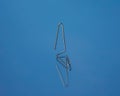 Realistic metal paper clip isolated on blue glass background.