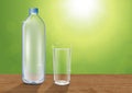Realistic mineral drinking water bottle and glass of water on wooden table on blurred green bokeh background, vector illustration