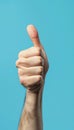Realistic photo of a hand making a thumbs up gesture against a plain blue background Royalty Free Stock Photo