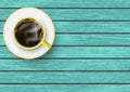 Realistic yellow and white coffee cup with saucer on blue vintage wooden table, top view Royalty Free Stock Photo