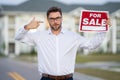 Realtor agent is a realtor with sign for sale in hand against the background on new apartment home background. Realtor