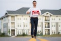 Realtor agent is a realtor with sign for sale in hand against the background on new apartment home background. Realtor