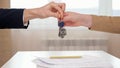 Realtor shakes hand and gives keys to client above table Royalty Free Stock Photo