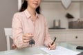 Realtor woman shows keys and writes documents. Close-up of hand. Concept of leasing and mortgage Royalty Free Stock Photo