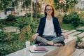 Realxed redhead woman does yoga outside at park sits in lotus pose meditates outdoors Royalty Free Stock Photo