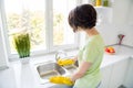 Rear back portrait of person rubber gloves hold sponge cleaning sink daylight window kitchen indoors