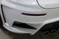 The rear bumper of a tuned car is white with a double exhaust nozzle, a diffuser and a red reflector in a vehicle tuning workshop Royalty Free Stock Photo