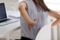 Rear closeup view girl feels backpain seated at workplace desk