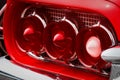 Rear Cluster Of An Old Timer Luxury Sports Car With Three Tail Lights With Red And White Glass Cones, Pipes Framed In Chrome