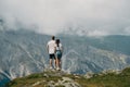 Rear of a couple enjoying a mountain covered with green grass, cloudy sky background Royalty Free Stock Photo