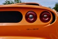 a rear end view of an orange sports car with red lights