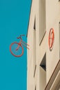 Rear half of vintage bicycle and a red wheel pinned to the wall of a minimalist building block with a turquoise blue sky Royalty Free Stock Photo