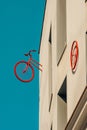 Rear half of vintage bicycle and a red wheel pinned to the wall of a minimalist building block with a turquoise blue sky Royalty Free Stock Photo