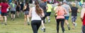 Rear horizontal view of runners racing on grass in a park