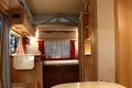 Rear interior part of retro designed trailer campervan Eriba 530 Rockabilly with visible bed, kitchen part and bathroom entrance.