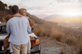 Rear of a man hugging his girlfriend outdoors at sunset, mountains view, love relationship Royalty Free Stock Photo