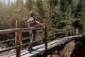 Rear on man traveler with backpack standing on bridge over river in forest. Traveling concept. Royalty Free Stock Photo