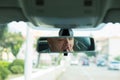 Rear mirror view reflection sleepy tired fatigued yawning exhausted young british business man driving his car in traffic after