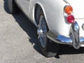 Rear of an old british classic car . Particular view of left tail light, shiny chrome bumper and left rear tire Royalty Free Stock Photo