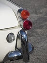 Rear of an old british classic car . Particular view of right tail light and shiny chrome bumper . The car is a Triumph TR3 model