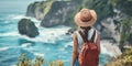 Rear panoramic view from behind a young white Caucasian woman standing on a cliff edge looking out to sea - gap year travel hiking Royalty Free Stock Photo